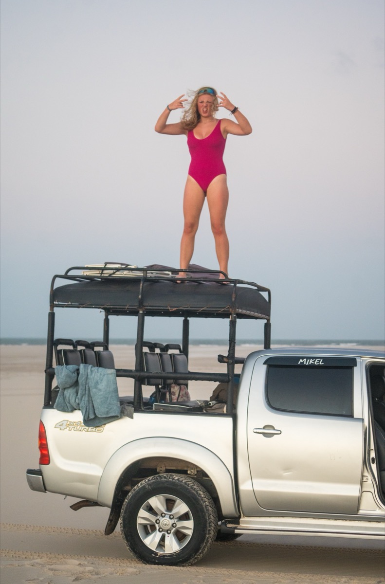Rider standing triumphant on roof of 4x4 truck on the beach — Local Secrets XP Brazil expedition adventure