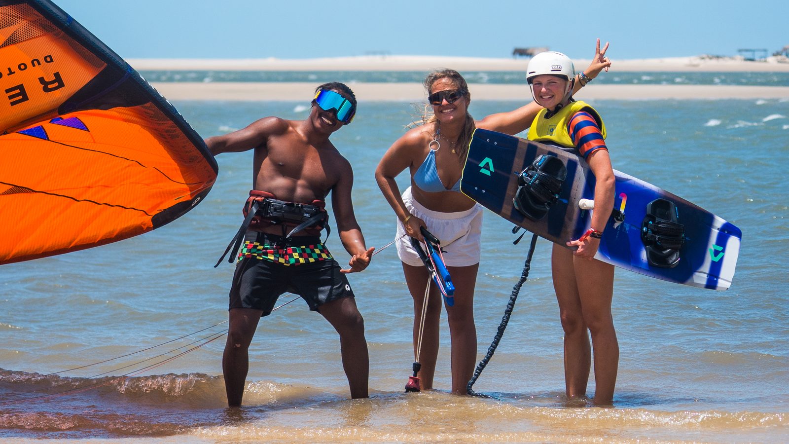 Three kitesurfers with kite and board on a sandbank in Atins, Lençóis Maranhenses, Brazil — small-group kitesurf travel with Local Secrets XP