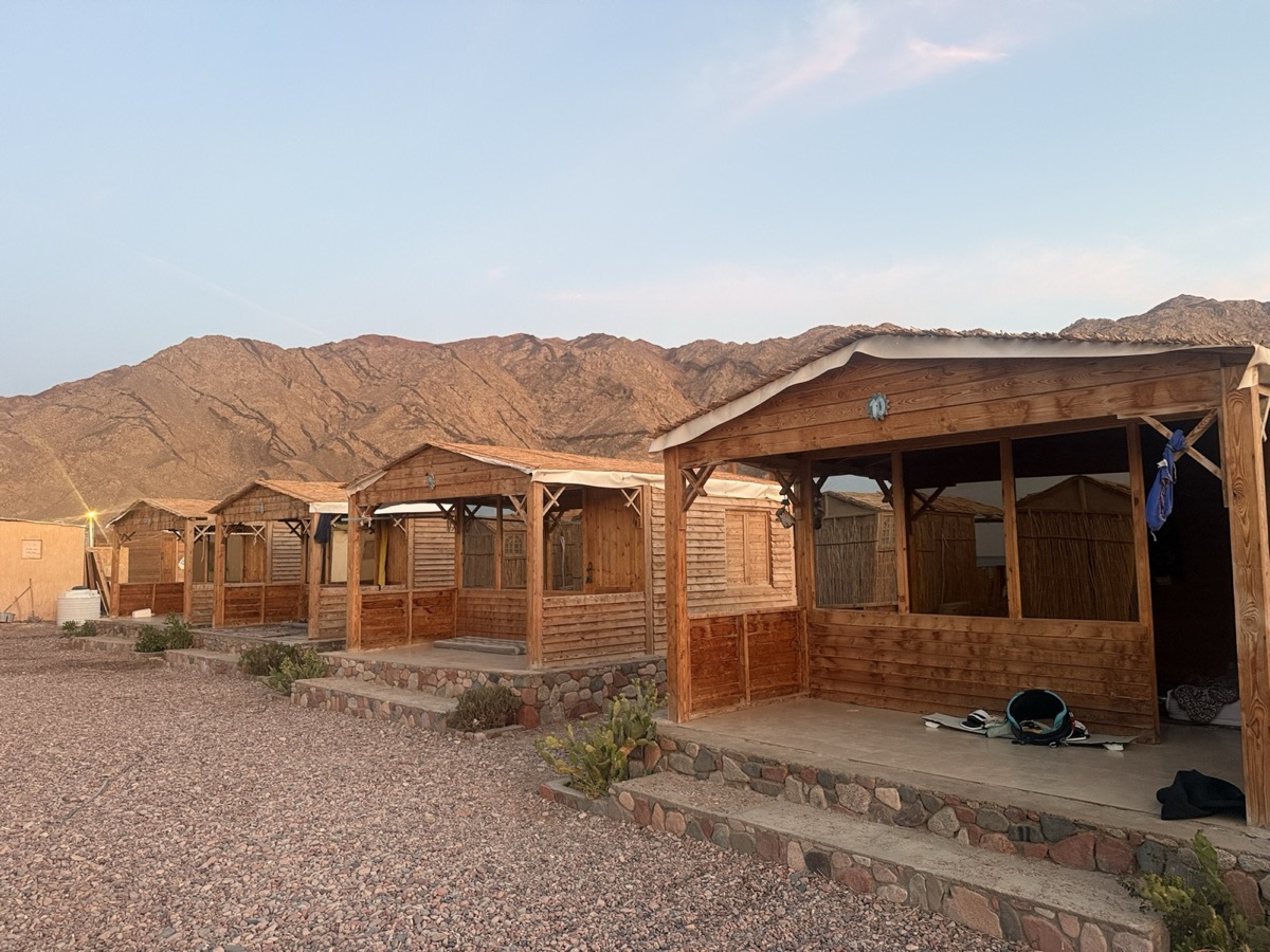 Wooden beach camp cabins at dusk with Sinai mountains — Blue Lagoon Dahab