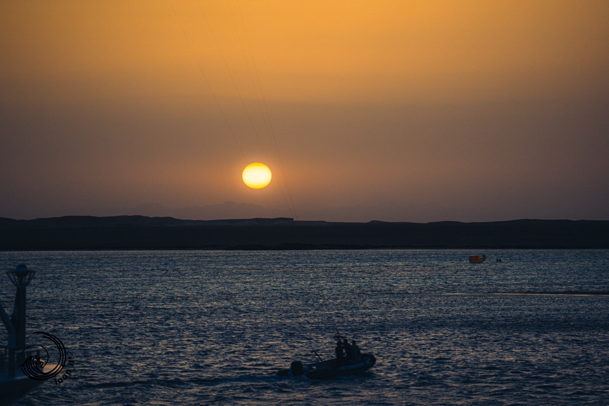 Deep orange Red Sea sunset with RIB support boat — end of kite session on Egypt expedition