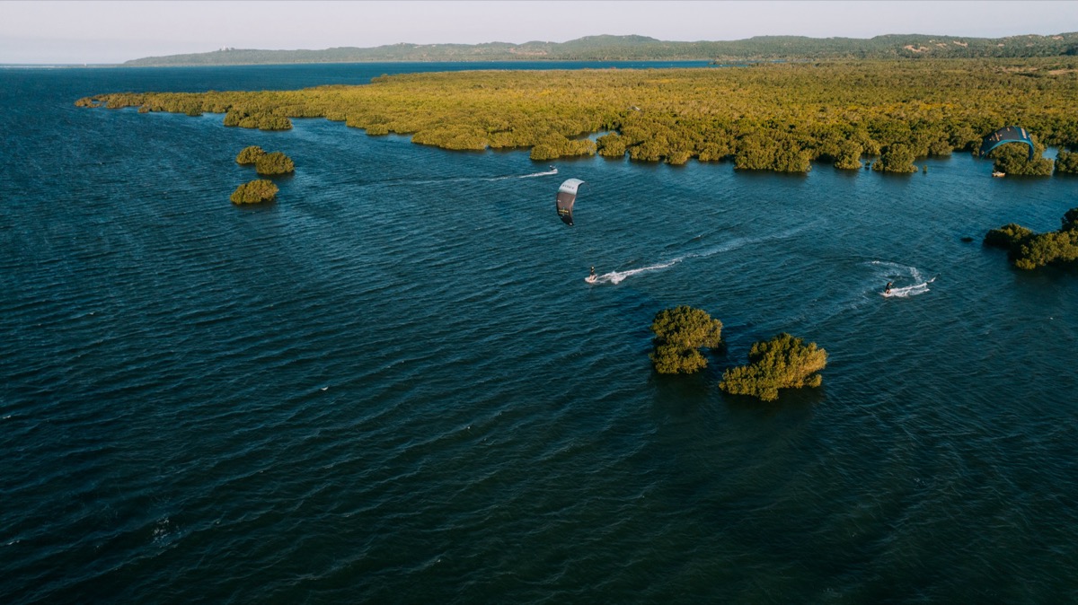 Aerial view of kitesurfers riding through mangrove-lined lagoon channels on Inhaca Island, Mozambique